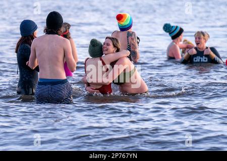 Des centaines de nageurs prennent un lever de soleil dans le Firth of Forth à Portobello Beach, Édimbourg, pour la Journée internationale des femmes. L'argent recueilli au cours de l'événement doit être donné à l'organisme de bienfaisance Women's Aid et cette année, c'est le 50th anniversaire de la succursale d'Édimbourg. Date de la photo: Mercredi 8 mars 2023. Banque D'Images