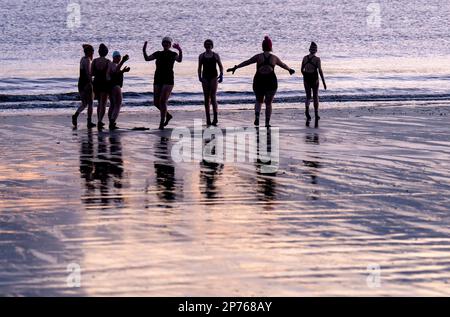 Des centaines de nageurs prennent un lever de soleil dans le Firth of Forth à Portobello Beach, Édimbourg, pour la Journée internationale des femmes. L'argent recueilli au cours de l'événement doit être donné à l'organisme de bienfaisance Women's Aid et cette année, c'est le 50th anniversaire de la succursale d'Édimbourg. Date de la photo: Mercredi 8 mars 2023. Banque D'Images