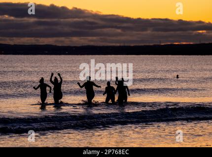 Des centaines de nageurs prennent un bain de soleil au Firth of Forth à Portobello Beach, Édimbourg, pour la Journée internationale de la femme. L'argent recueilli au cours de l'événement doit être donné à l'organisme de bienfaisance Women's Aid et cette année, c'est le 50th anniversaire de la succursale d'Édimbourg. Date de la photo: Mercredi 8 mars 2023. Banque D'Images