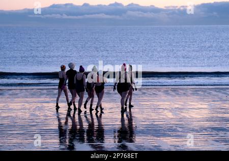 Des centaines de nageurs prennent un bain de soleil au Firth of Forth à Portobello Beach, Édimbourg, pour la Journée internationale de la femme. L'argent recueilli au cours de l'événement doit être donné à l'organisme de bienfaisance Women's Aid et cette année, c'est le 50th anniversaire de la succursale d'Édimbourg. Date de la photo: Mercredi 8 mars 2023. Banque D'Images