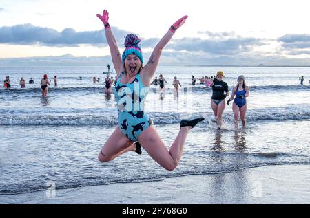 Des centaines de nageurs prennent un lever de soleil dans le Firth of Forth à Portobello Beach, Édimbourg, pour la Journée internationale des femmes. L'argent recueilli au cours de l'événement doit être donné à l'organisme de bienfaisance Women's Aid et cette année, c'est le 50th anniversaire de la succursale d'Édimbourg. Date de la photo: Mercredi 8 mars 2023. Banque D'Images