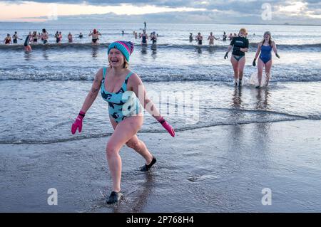 Des centaines de nageurs prennent un bain de soleil au Firth of Forth à Portobello Beach, Édimbourg, pour la Journée internationale de la femme. L'argent recueilli au cours de l'événement doit être donné à l'organisme de bienfaisance Women's Aid et cette année, c'est le 50th anniversaire de la succursale d'Édimbourg. Date de la photo: Mercredi 8 mars 2023. Banque D'Images