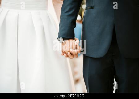 Mariée et marié tenant leurs mains pendant la cérémonie de mariage - concept d'amour Banque D'Images