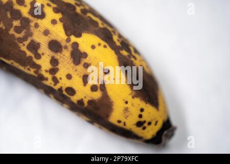 Banane avec taches sombres. Banane mûre. Isolé sur fond blanc. Mise au point sélective. Banque D'Images