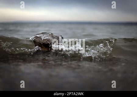 Dinning, Allemagne. 08th mars 2023. Une pierre lavée par les vagues se trouve sur la rive du lac Ammersee, qui est recouvert de nuages de pluie. Le service météorologique allemand prévoit la pluie, la neige et les tempêtes pour les jours à venir. Credit: Karl-Josef Hildenbrand/dpa/Alay Live News Banque D'Images