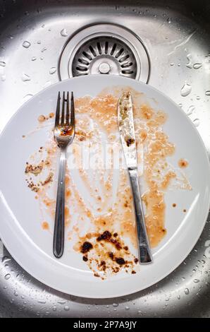 Vaisselle sale dans l'évier de cuisine. Plats et ustensiles en porcelaine tachée à la sauce alimentaire, personne, vue de dessus. Banque D'Images