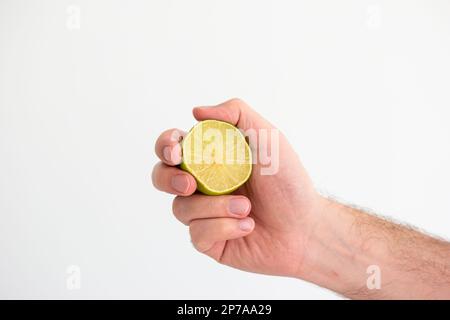 Vert frais moitié chaux tenue à la main par le mâle caucasien main gros plan isolé sur blanc. Banque D'Images