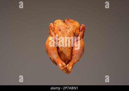 Poulet entier frais, cru et prêt à être assaisonné. Gros plan en studio, isolé sur fond marron. Banque D'Images