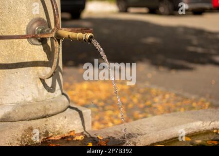 Vieille pierre et fontaine publique d'eau potable en métal sculpté. Ville européenne, jour d'été, gros plan, pas de monde. Banque D'Images