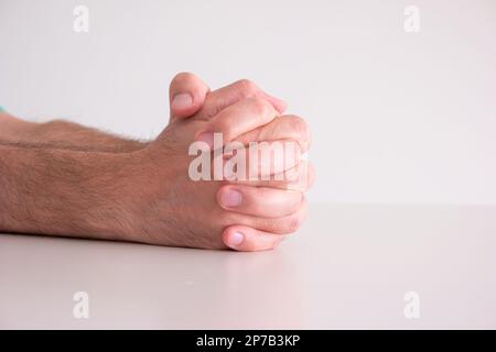 Les mains masculines caucasiennes se sont accrochées ensemble dans la prière, isolées sur fond blanc. Banque D'Images