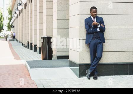Portrait d'un homme d'affaires afro-américain noir en costume à l'extérieur, posé en pleine croissance tout en étant debout dans la rue Banque D'Images