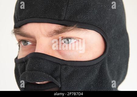 Visage masculin caucasien portant un masque de ski en tissu noir. Gros plan, non reconnaissable. Banque D'Images