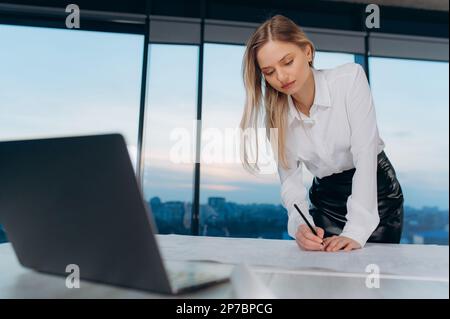 une femme planifie l'horaire de travail, écrit sur papier, femme d'affaires Banque D'Images