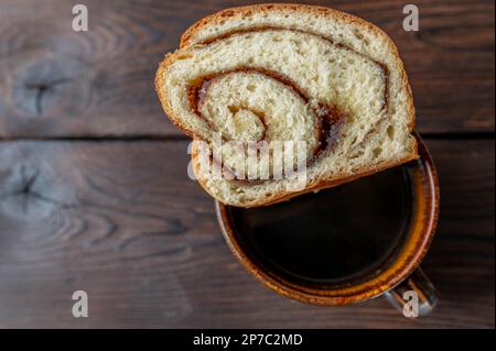 Café et gâteau avec une tranche de gâteau à la levure et garniture en rouleau de cannelle Banque D'Images