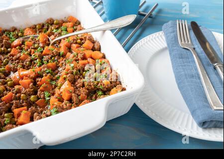 Ragoût de viande hachée cuit avec du bœuf haché, des petits pois et des carottes et servi chaud et prêt à manger dans un bol sur une table de cuisine Banque D'Images