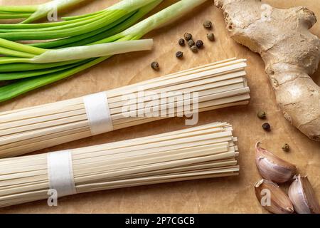 Gros plan sur les nudles et les épices crues. Paquets de pâtes végétaliennes japonaises séchées à base de farine de blé, de gingembre, d'ail et de scallion préparés pour la cuisson. Banque D'Images