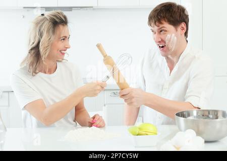 Mari et femme querelle dans la cuisine pendant la cuisine. Confrontation comique et gaie entre l'homme et la femme dans la cuisine. Arrière-plan... Banque D'Images