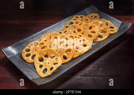 émincé de racines de lotus frite sur une assiette noire, cuisine asiatique. Banque D'Images