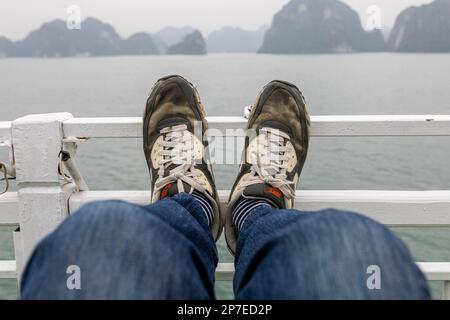 Une paire d'anciennes baskets Nike Air colorées reposant sur un rail de navire à Ha long Bay, au Vietnam. Banque D'Images