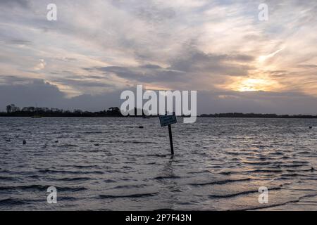 Cette route inonde chaque panneau de la route de marée partiellement submergé à marée haute au coucher du soleil à Bosham West Sussex angleterre Banque D'Images