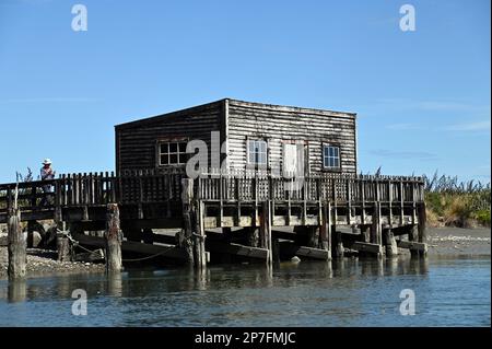 Le quai, la jetée et la maison de bateau à la colonie de la côte ouest d'Okarito. Pendant la ruée vers l'or de 1860s, Okarito a vu plus de 500 mineurs débarquer en une journée. Banque D'Images