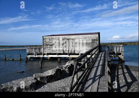 Le quai, la jetée et la maison de bateau à la colonie de la côte ouest d'Okarito. Pendant la ruée vers l'or de 1860s, Okarito a vu plus de 500 mineurs débarquer en une journée. Banque D'Images