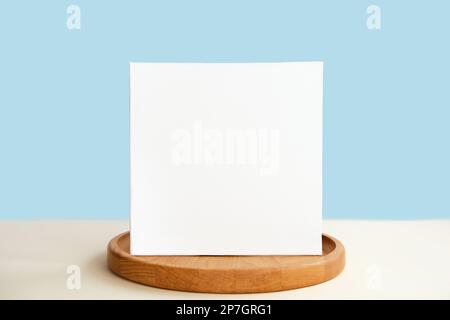 Carte de vœux vierge, maquette d'invitation. Vue avant. Assiette en bois moderne, maquette en papier sur table beige. Copier l'espace. Modèle minimal de marque commerciale. Donc Banque D'Images