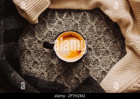 Vue de dessus d'une tasse noire avec café aromatique fort, qui se tient parmi les pulls en laine chaude. Une boisson chaude en saison froide. Banque D'Images