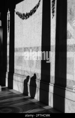 Image en noir et blanc des ombres de deux personnes sur les murs de la passerelle en marbre du Musée d'Art petit Palais Paris France. Banque D'Images