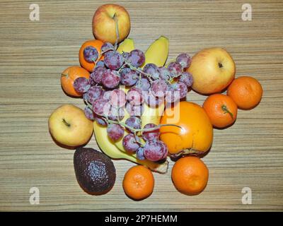 fruits sur fond de bois - clémentines, persimmon, pommes, pommes, bananes, avocat, raisins roses Banque D'Images