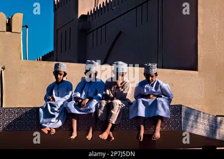 Garçons avec des chapeaux kuma sur le toit, Nizwa, Oman Banque D'Images