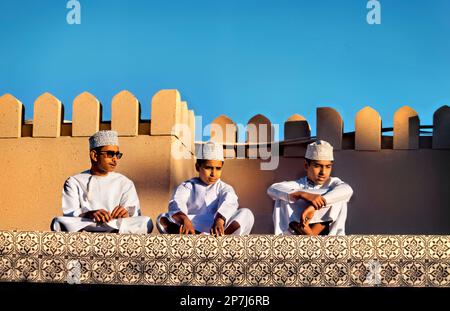 Garçons avec des chapeaux kuma sur le toit, Nizwa, Oman Banque D'Images