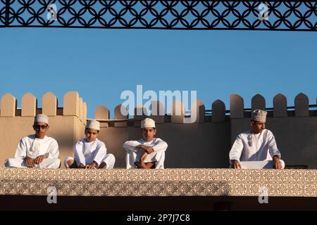 Garçons avec des chapeaux kuma sur le toit, Nizwa, Oman Banque D'Images