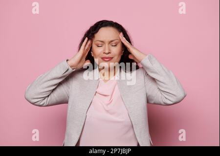 Femme malsaine frottant les temples, guérir les maux de tête, souffre de tension, migaine, stress, grimaces dans la douleur. Problèmes de santé Banque D'Images