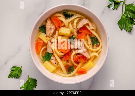 Soupe au poulet avec nouilles et légumes dans un bol blanc Banque D'Images