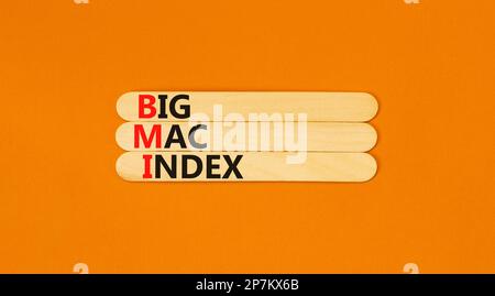 BMI gros symbole d'index mac. Concept mots BMI Big mac index sur bâton de bois sur une belle table orange orange fond orange. Business et BMI Big mac inde Banque D'Images