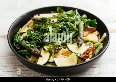 Bol avec tagliatelle maison aux asperges vertes, courgettes et épinards. Banque D'Images