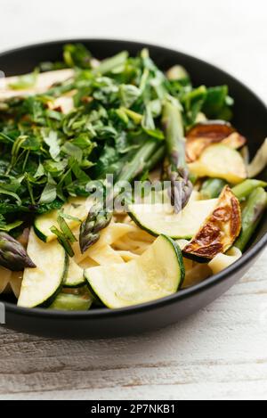 Bol avec tagliatelle maison aux asperges vertes, courgettes et épinards. Banque D'Images