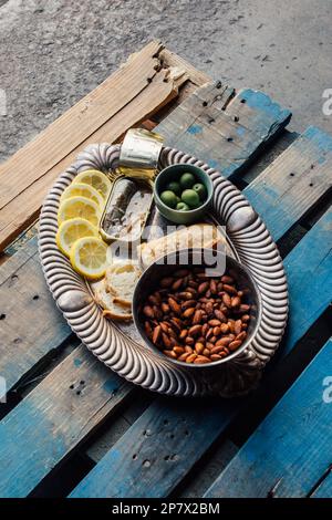 vue en grand angle de la boîte de poisson sardines plateau d'en-cas argent avec amandes, pain, olives vertes, tranches de citron sur palette en bois Banque D'Images