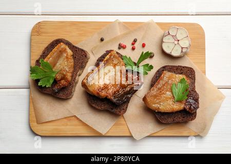 Pain de seigle avec de savoureux crépitements frits sur une table en bois blanc, vue de dessus. Lard de porc cuit Banque D'Images