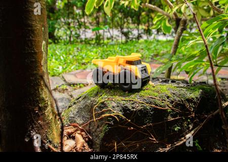 Une photo après quelques modifications. Un camion-benne jaune sur une pierre de mousse. Banque D'Images
