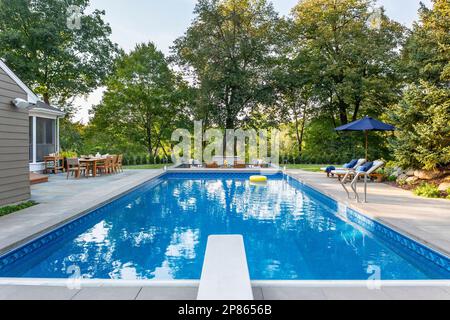 Extérieur d'une maison avec zone de foyer en contrebas et piscine extérieure Banque D'Images