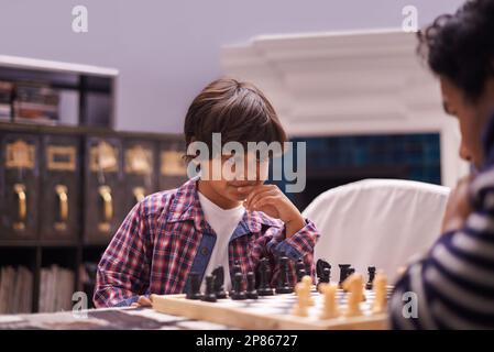 Planifier sa prochaine étape. un père et un fils jouant aux échecs à la maison. Banque D'Images