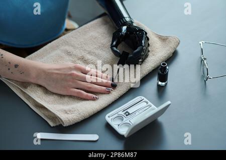 Gros plan de la jeune femme avec la main prothétique se manucure, elle peint ses ongles avec du vernis Banque D'Images