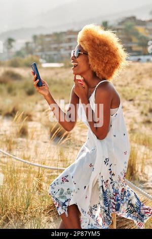 Une femme afro rit tout en parlant un selfie avec le mobile Banque D'Images