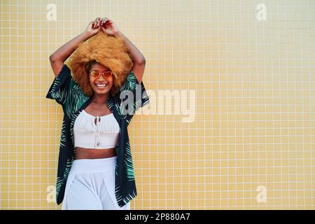 Femme afro moderne souriante en posant avec des vêtements d'été Banque D'Images