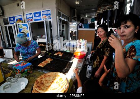 Des femmes ouzbèkes se tenant chez un vendeur de Samsa sur le marché de Boukhara, en Ouzbékistan. Banque D'Images