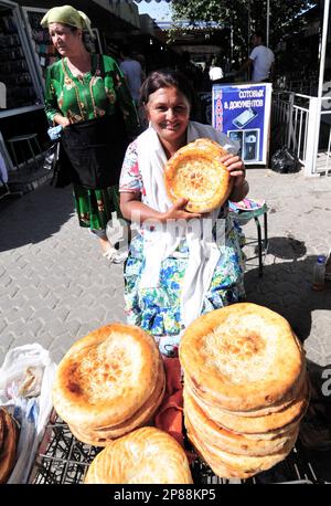 Une femme ouzbek vendant OBI non- un pain ouzbek / tadjik traditionnel vendu sur le marché à Boukhara, Ouzbékistan. Banque D'Images