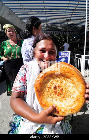 Une femme ouzbek vendant OBI non- un pain ouzbek / tadjik traditionnel vendu sur le marché à Boukhara, Ouzbékistan. Banque D'Images