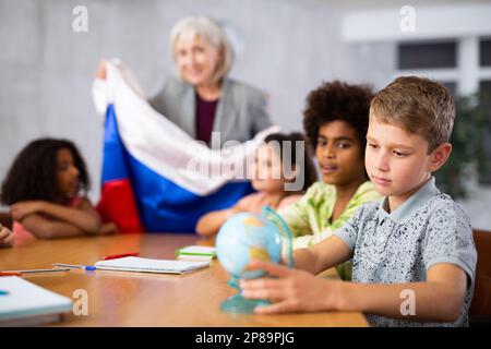 Femme enseignante enseignante enseignante enseignante montrant le drapeau russe aux enfants de la classe de géographie drapeau arc-en-ciel aux enfants de la classe de géographie Banque D'Images